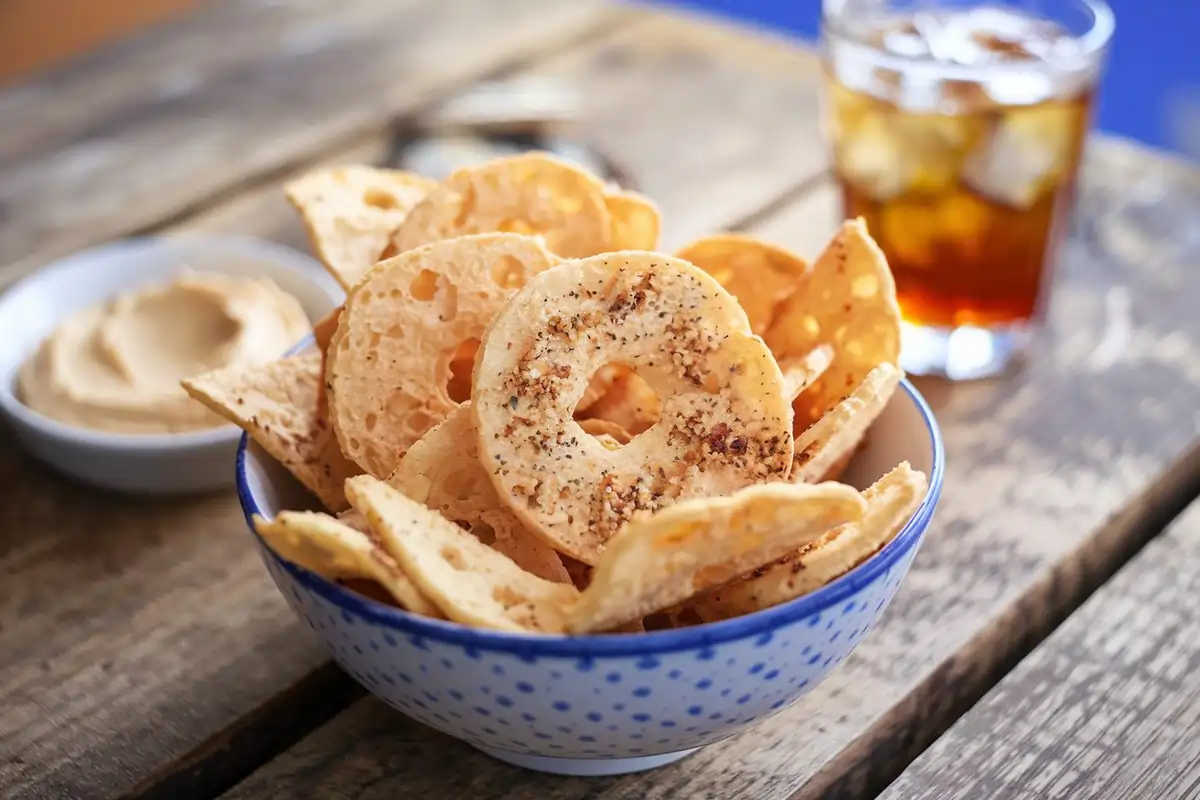 A bowl of golden-brown bagel chips garnished with everything bagel seasoning.